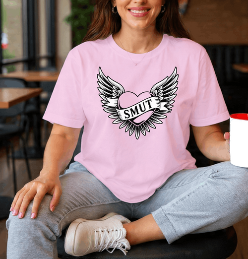 Person wearing a pink t-shirt with a graphic design and holding a Starbucks cup in a casual setting.