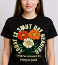 Person wearing a black t-shirt with colorful floral design and text.