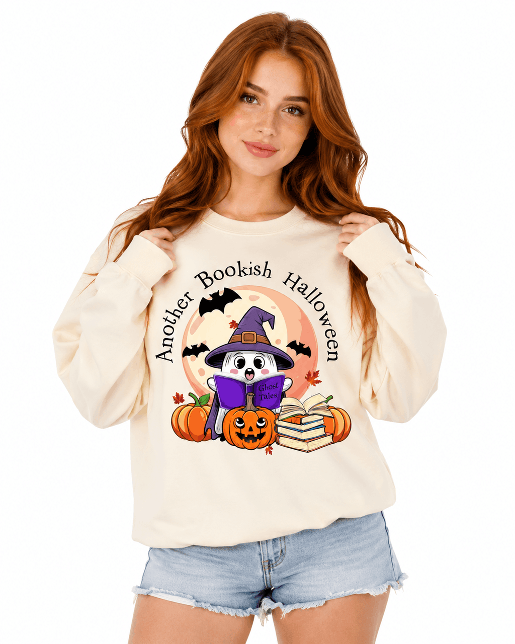 Cream unisex crewneck sweatshirt with cute illustrated witch reading a book design surrounded by pumpkins and autumn leaves, perfect for Halloween-loving readers