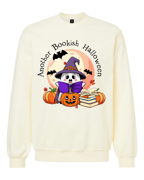 An off-white crewneck sweatshirt featuring a colorful graphic of a cartoon ghost in a witch hat reading a book, surrounded by pumpkins, books, bats, and the text 'Another Bookish Halloween'.