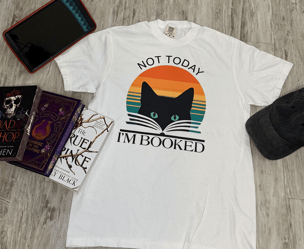 White t-shirt with a cute cat graphic and 'Not Today, I'm Booked' text on it. Your go-to shirt for going out and about.